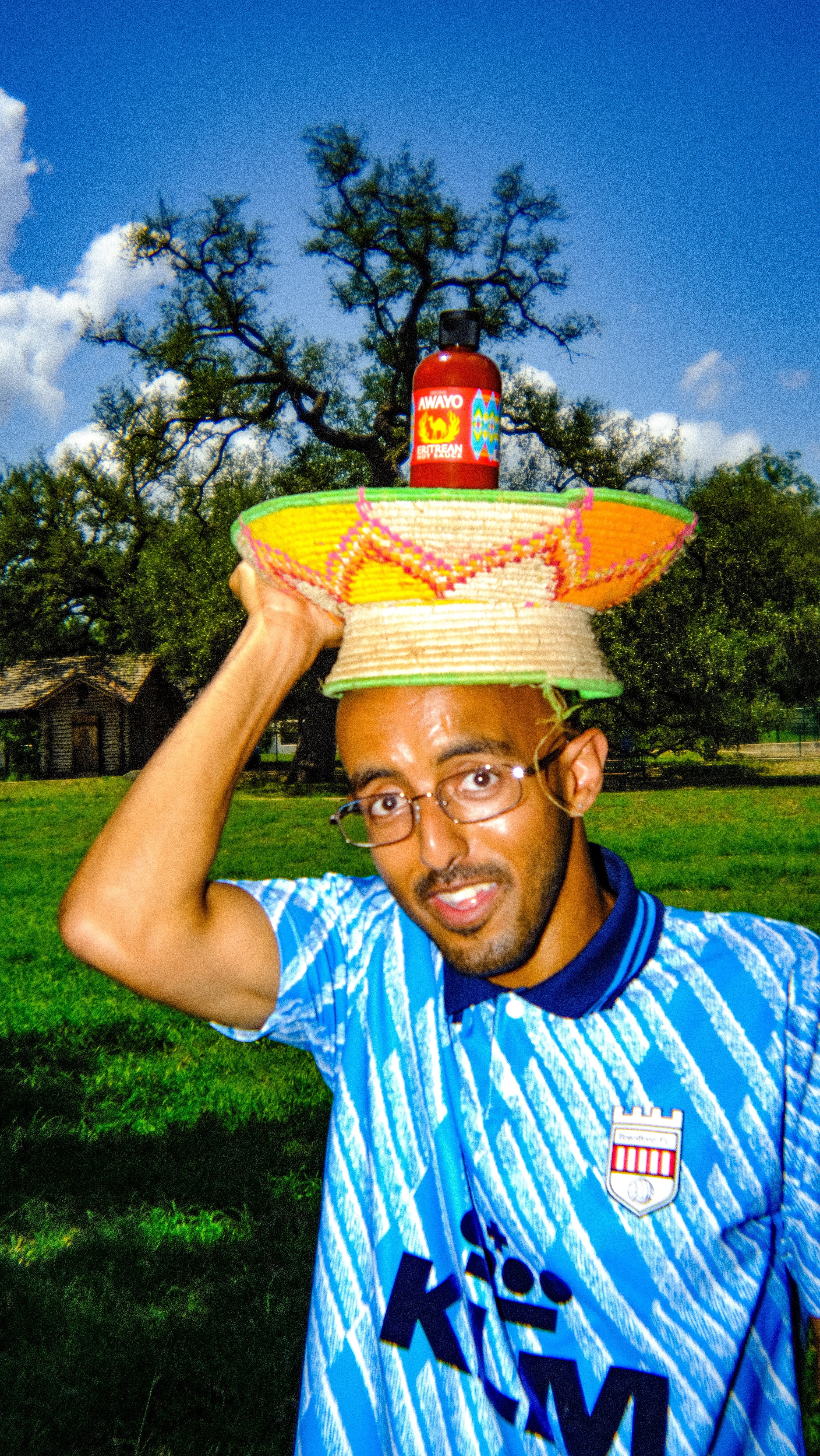 Person with a basket on his head that has Awayo Eritrean Hot Sauce sitting on top.